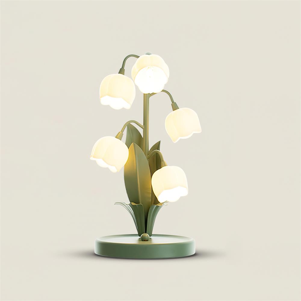 Clérachic table lamp with five glowing bell shades on green stems, with leaf-shaped metal blades, on a soft cream backdrop.
