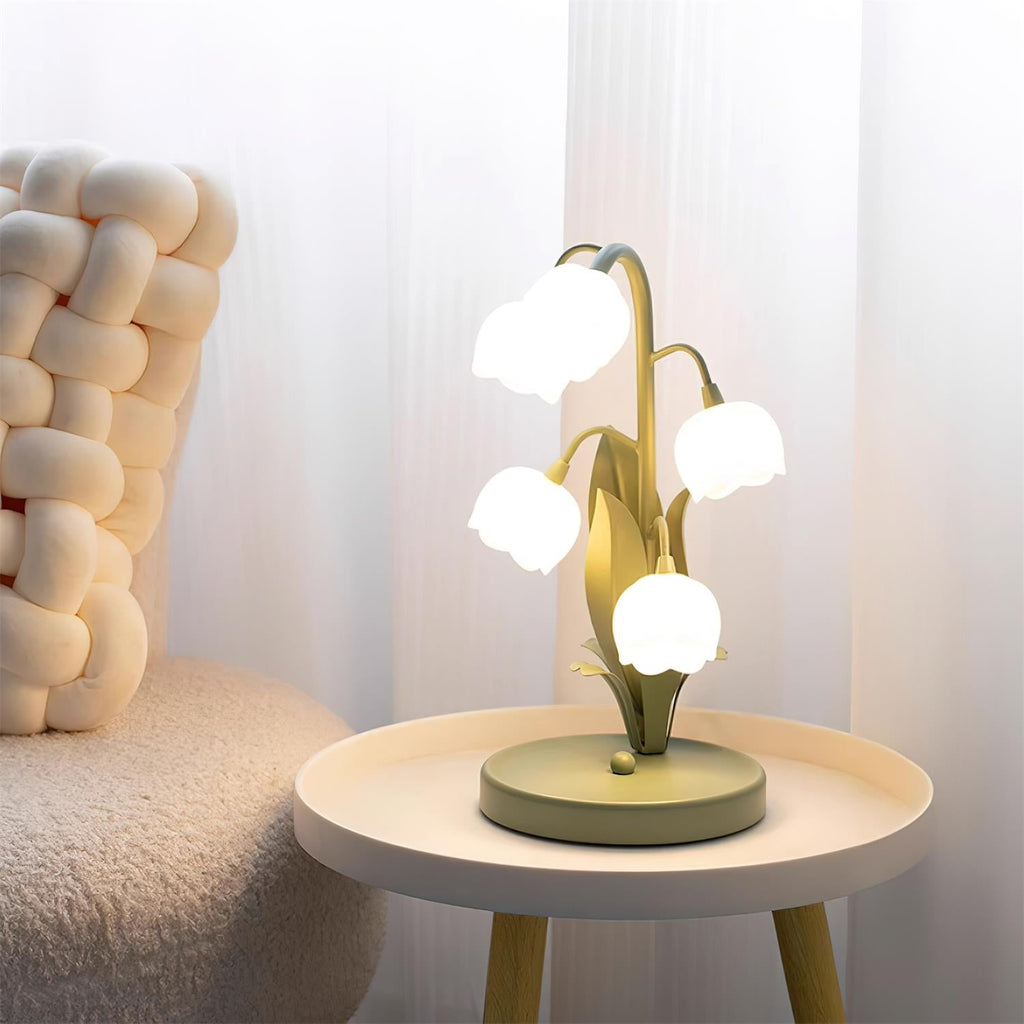 Clérachic table lamp lit on a small round white tray table with a chunky cream knitted cushion and white curtains behind it.
