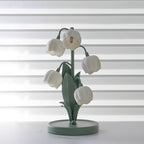 The Clérachic table lamp switched off, its white bell shades and green stems against striped window blinds.