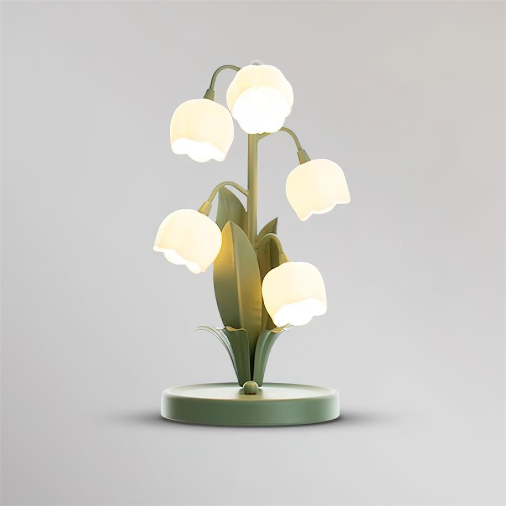 Clérachic table lamp lit on a light grey backdrop, its five bell shades glowing above the round green base.