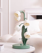 A Clérachic table lamp, unlit, on a white marble table in front of a cream sofa and a white mantel.