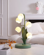 This Clérachic table lamp glows on a white table beside a cream sofa, with a small bust and a white fireplace behind.