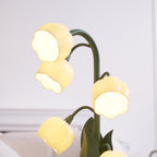 Close view of the lit bell shades on this Clérachic table lamp, with cream furniture softly blurred behind it.