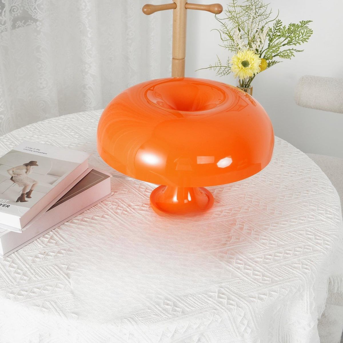 Close view of the rounded orange shade with its central opening on this Clérachic table lamp, on a white lace cloth.