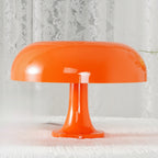 Low close view of the wide orange shade and slim stem of this Clérachic lamp, standing on a white lace cloth.