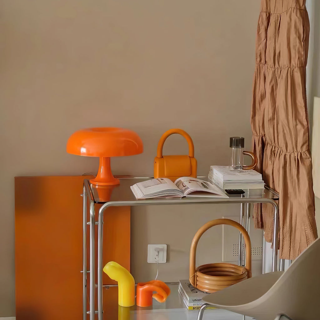 Orange Clérachic mushroom lamp on a chrome drinks trolley in a room with orange accessories and a tan wall.
