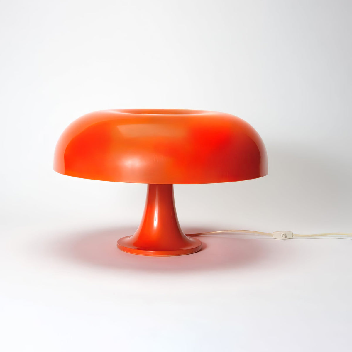 Orange Clérachic dome lamp on a white studio background, with a soft shadow under the shade and a pale cord behind.
