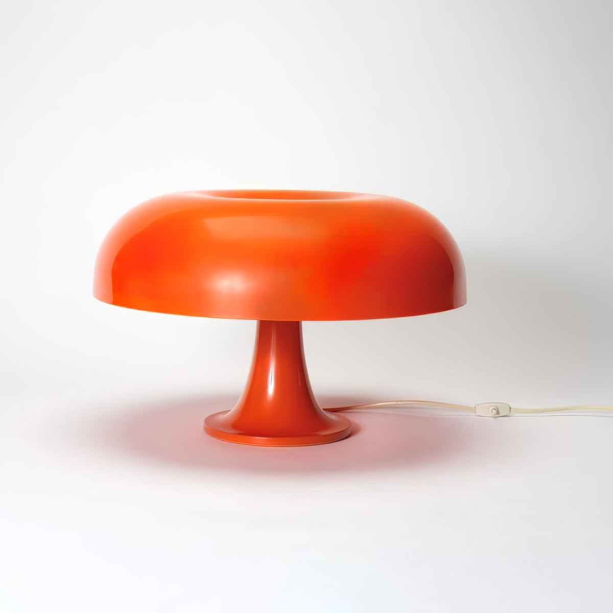 Orange mushroom lamp from Clérachic on a white studio surface, with soft shadow and a light cord at the back.