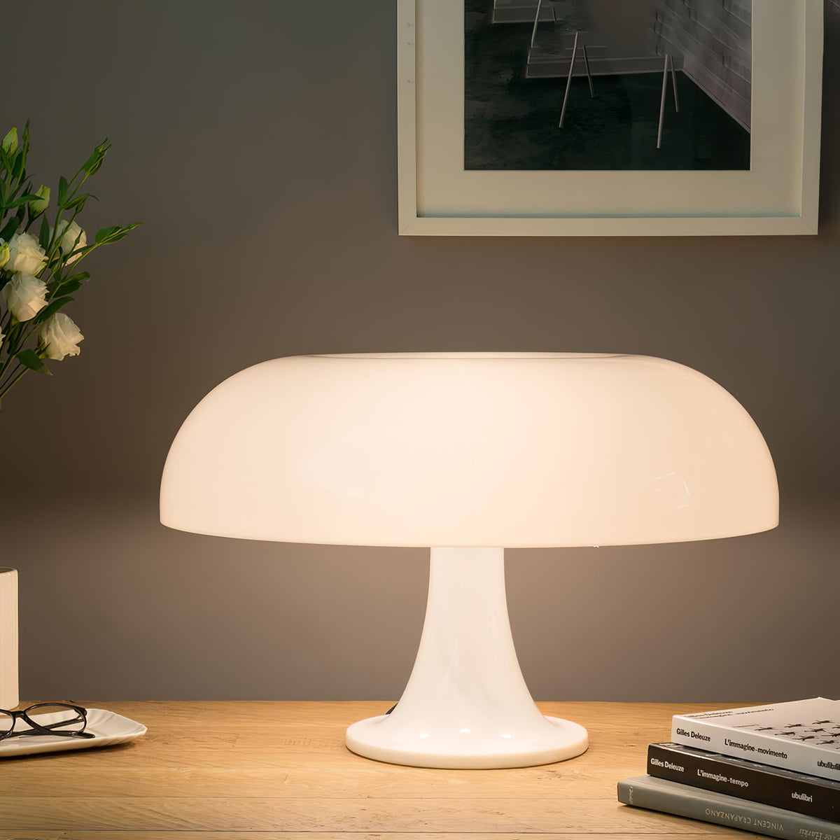 Close view of this Clérachic white dome lamp on a wooden desk, its shade glowing softly with glasses and books at the side.