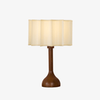 Clérachic table lamp on a white backdrop, a scalloped beige fabric shade above a slim wooden stem and round base.