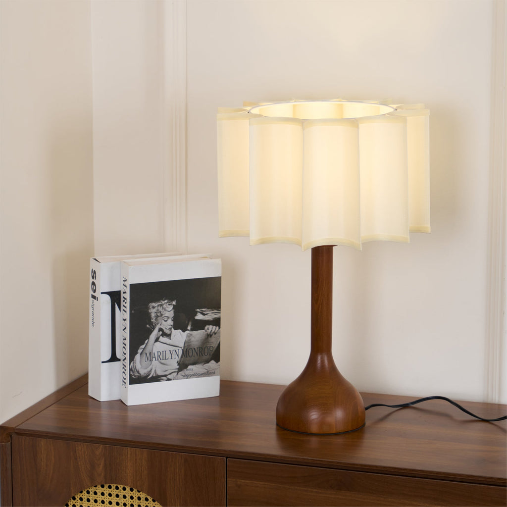 Clérachic table lamp on a sideboard beside a black and white book, warm light inside the scalloped shade.