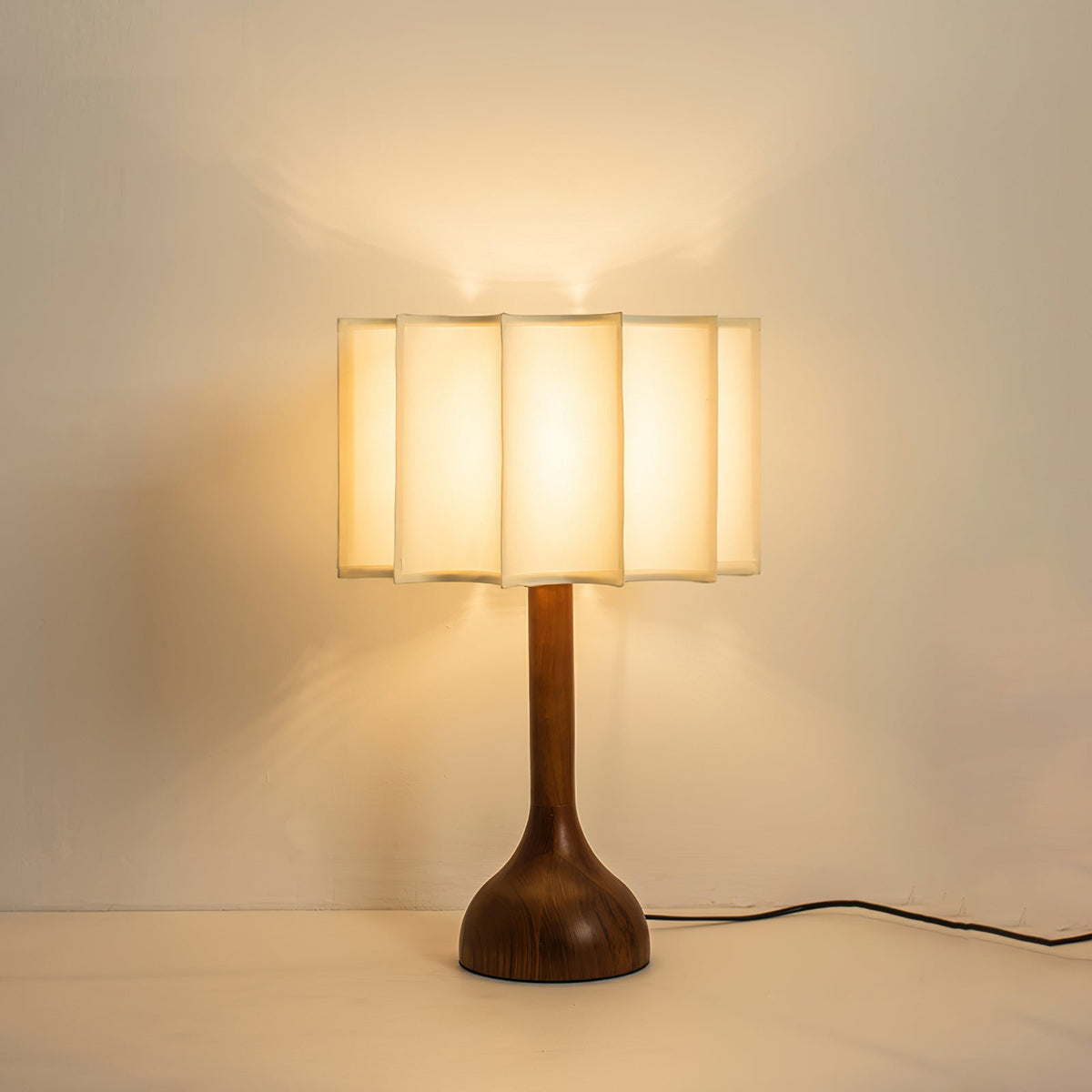 Clérachic table lamp glowing amber in a warm room, the shade lit from within above its dark wooden base.