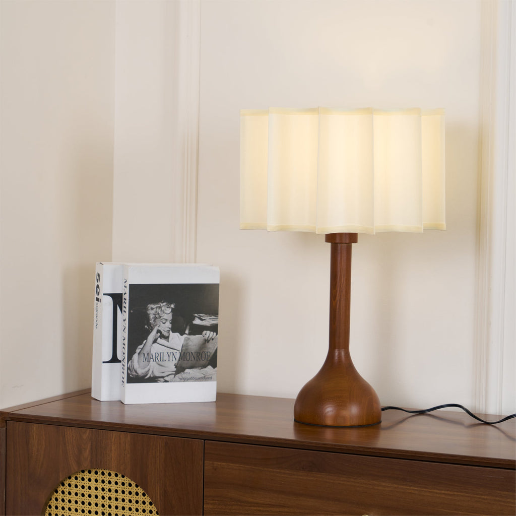 Low-angle view of a Clérachic table lamp on a cabinet, its soft beige shade and bulb-shaped wooden base in view.