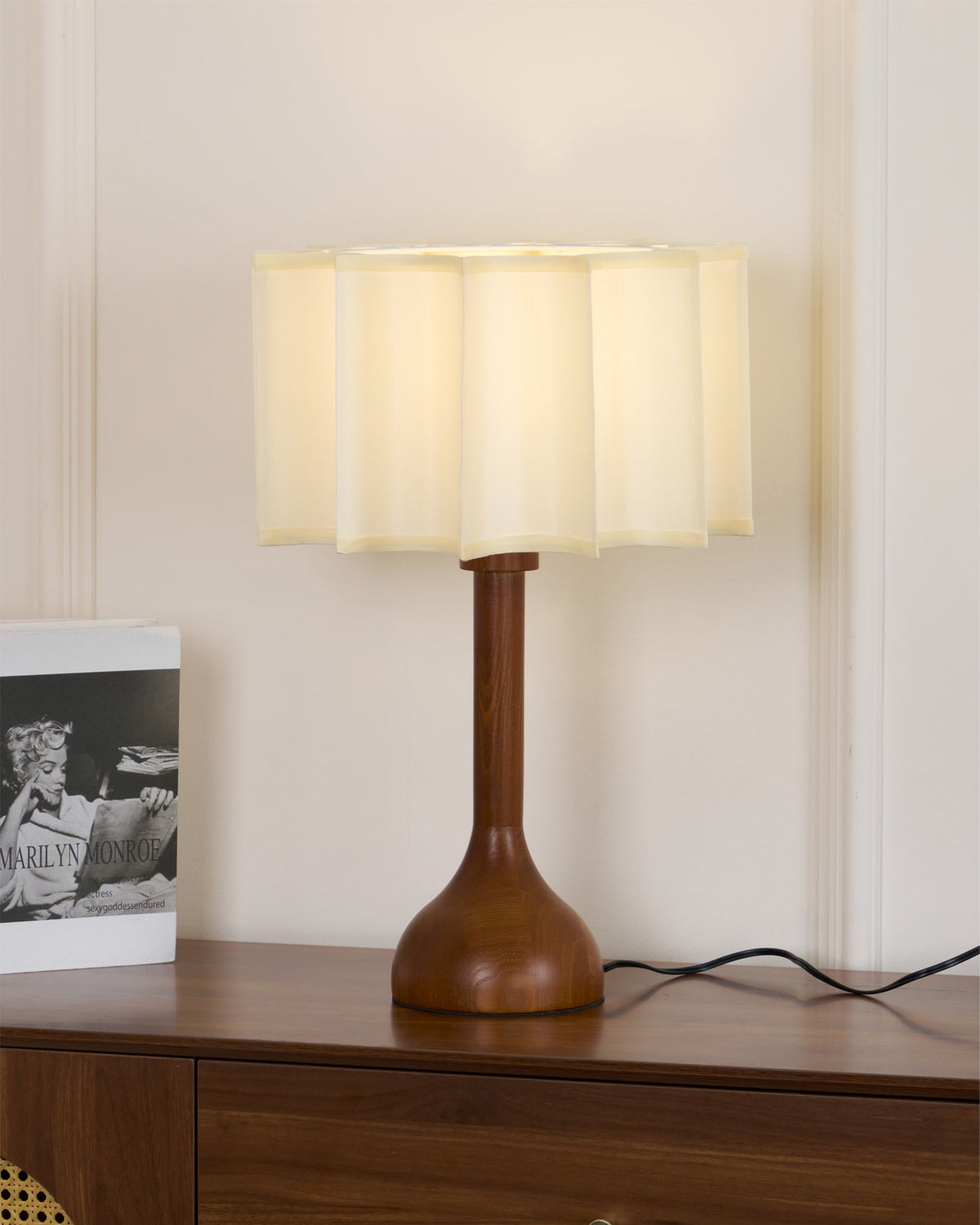 Clérachic table lamp on a sideboard, wood grain on the stem and base and a black cord curling to the right.