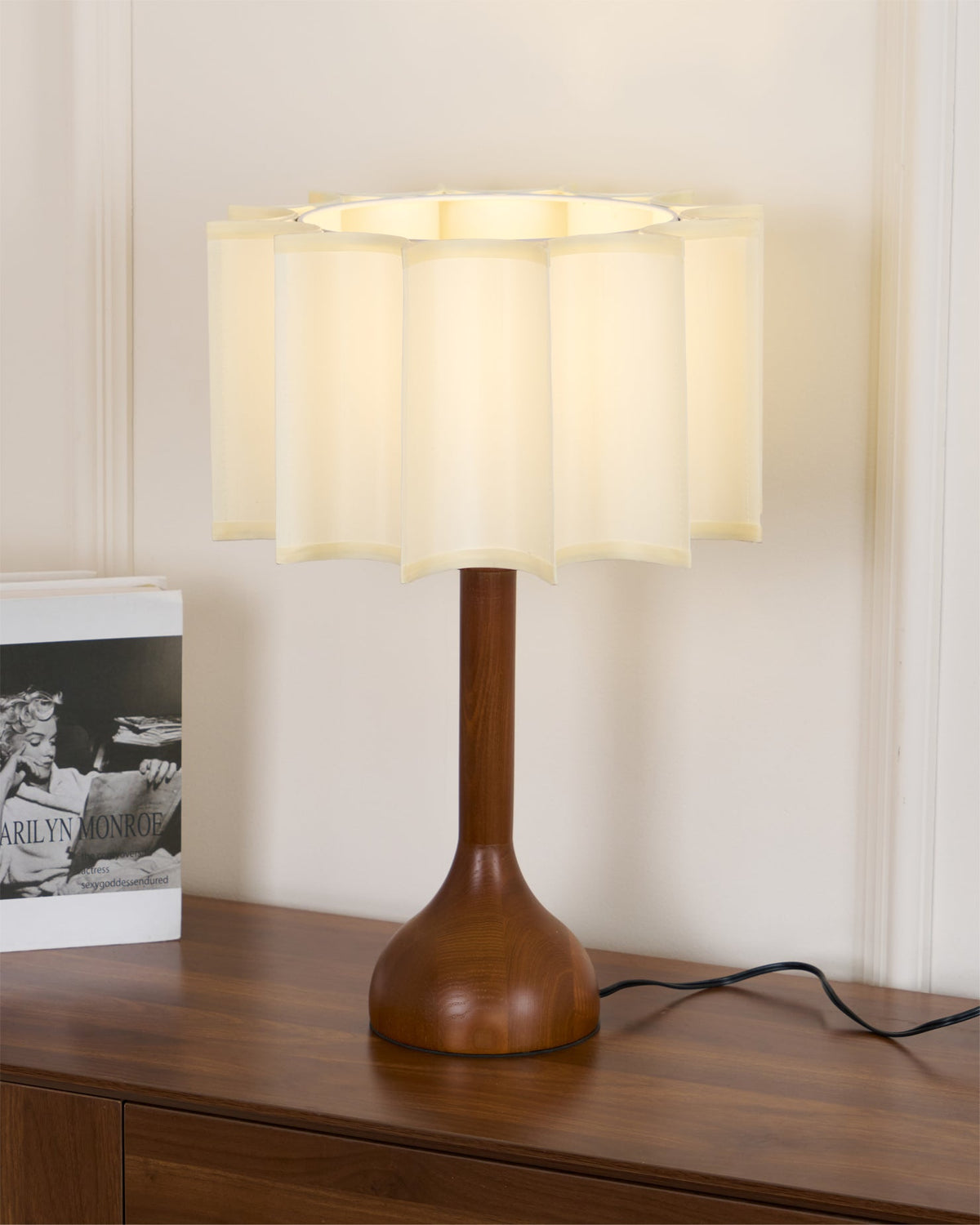 Close view of a Clérachic table lamp lit from within, its crinkled beige shade open at the top.