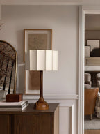 Wider view of a Clérachic table lamp on a cabinet, a stack of books and a framed sketch beside it.