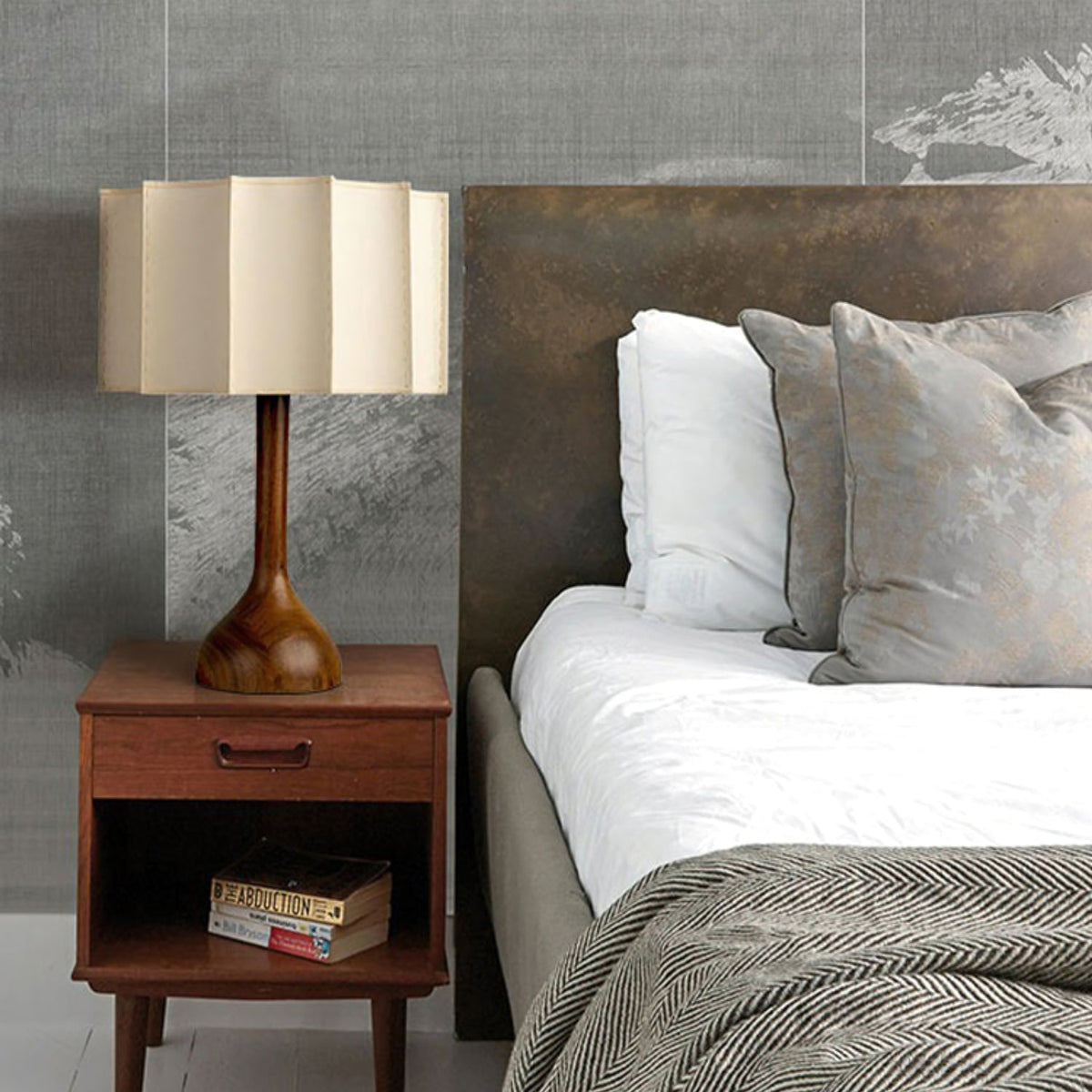 Clérachic table lamp on a mid-century bedside table, with white bedding and a grey throw beyond.