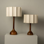 Two Clérachic table lamps of different heights on a white plinth against a sage-grey wall.