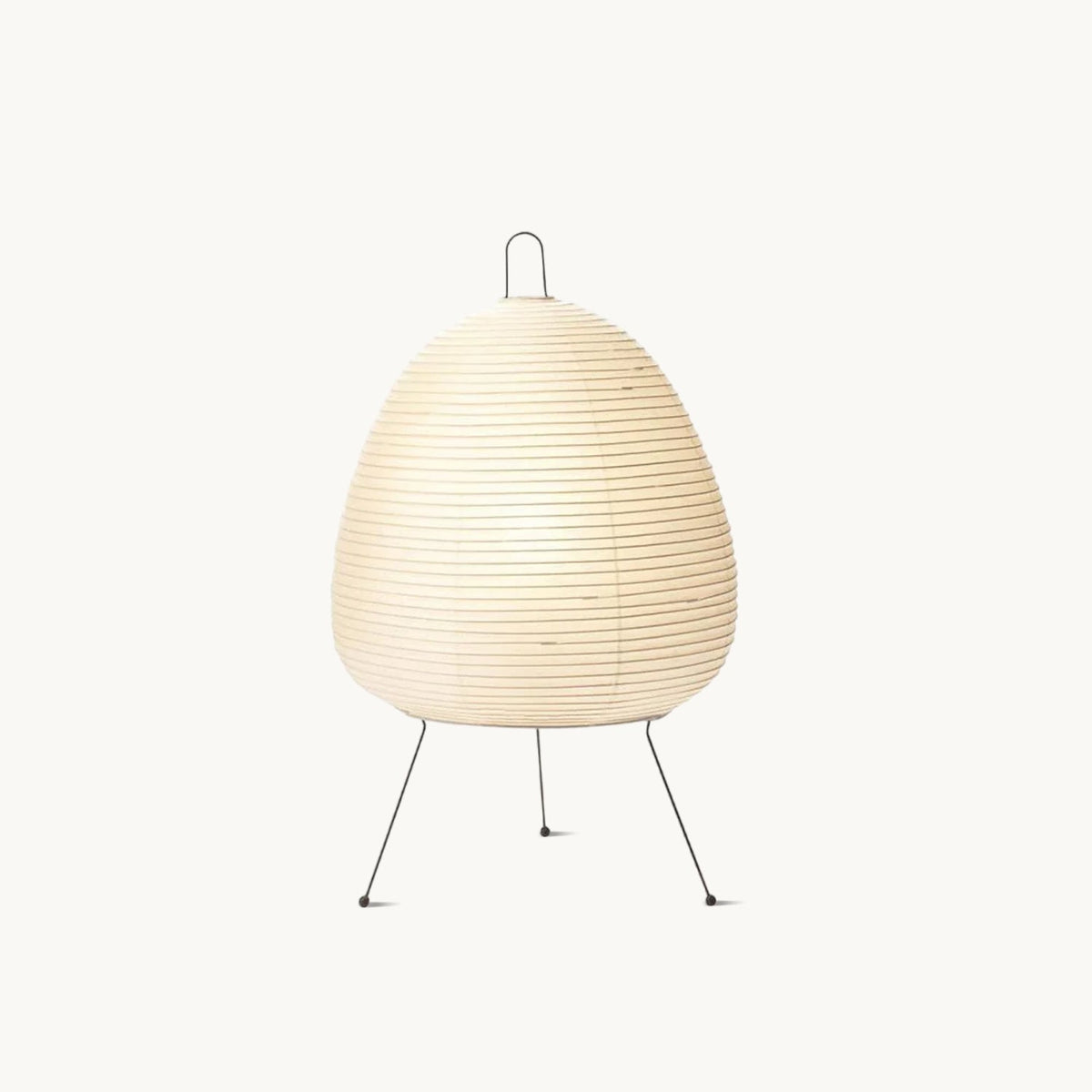 Pleated paper shade of this Clérachic table lamp on three slim black metal legs, shown on a plain white backdrop.
