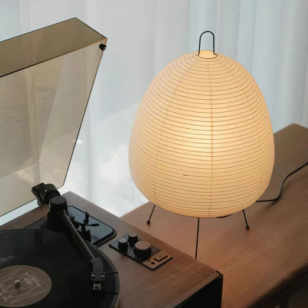 Close view of this Clérachic table lamp lit beside a record player, the pleated paper shade glowing warm amber.