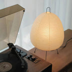 Close view of this Clérachic table lamp lit beside a record player, the pleated paper shade glowing warm amber.