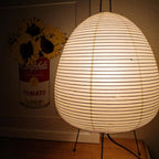 Close view of the ribbed paper shade on this Clérachic table lamp, glowing in front of a pop-art style poster.