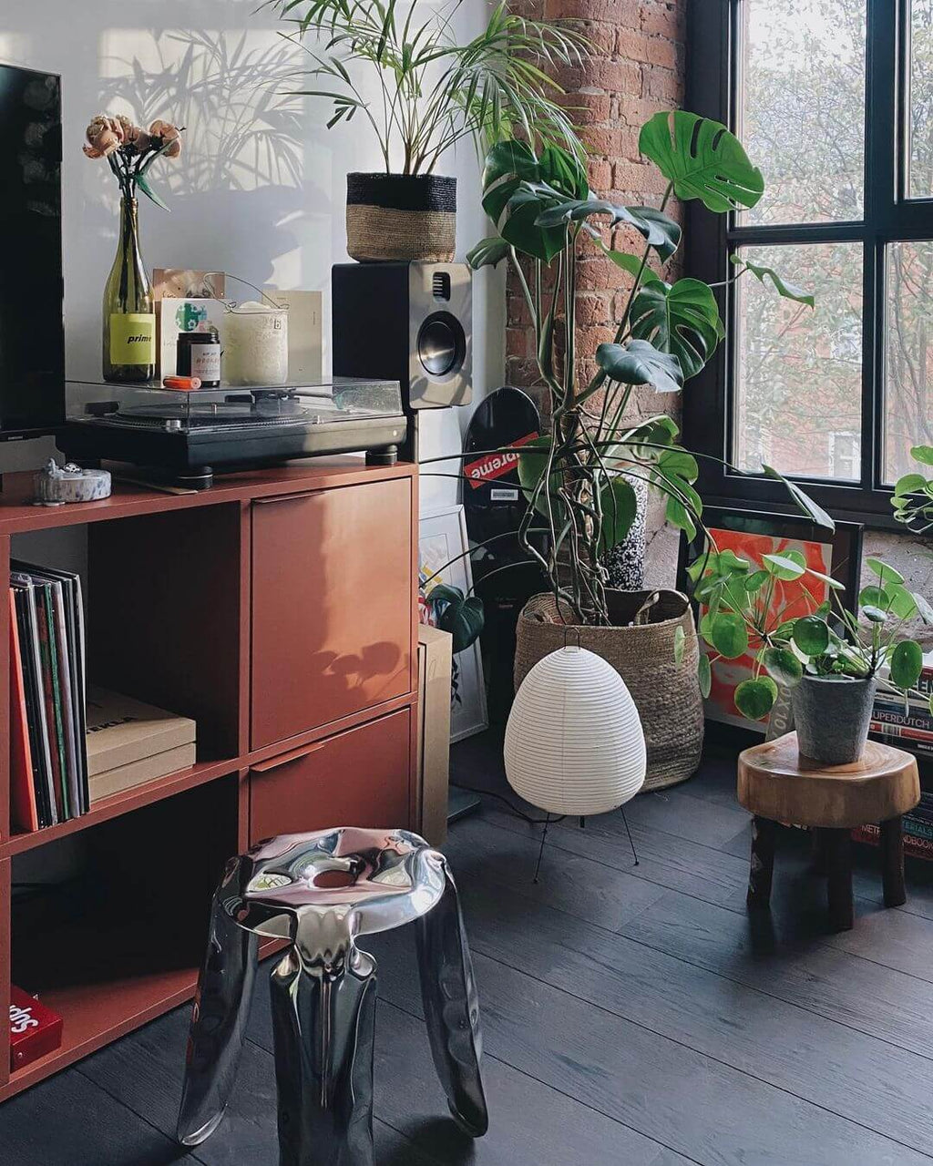 Small Clérachic egg-shaped lamp in the corner of a living space with plants, a record player and a red cabinet.