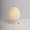 Egg-shaped Clérachic paper lamp on a plain grey backdrop, its shade finely ribbed above three black legs with round feet.