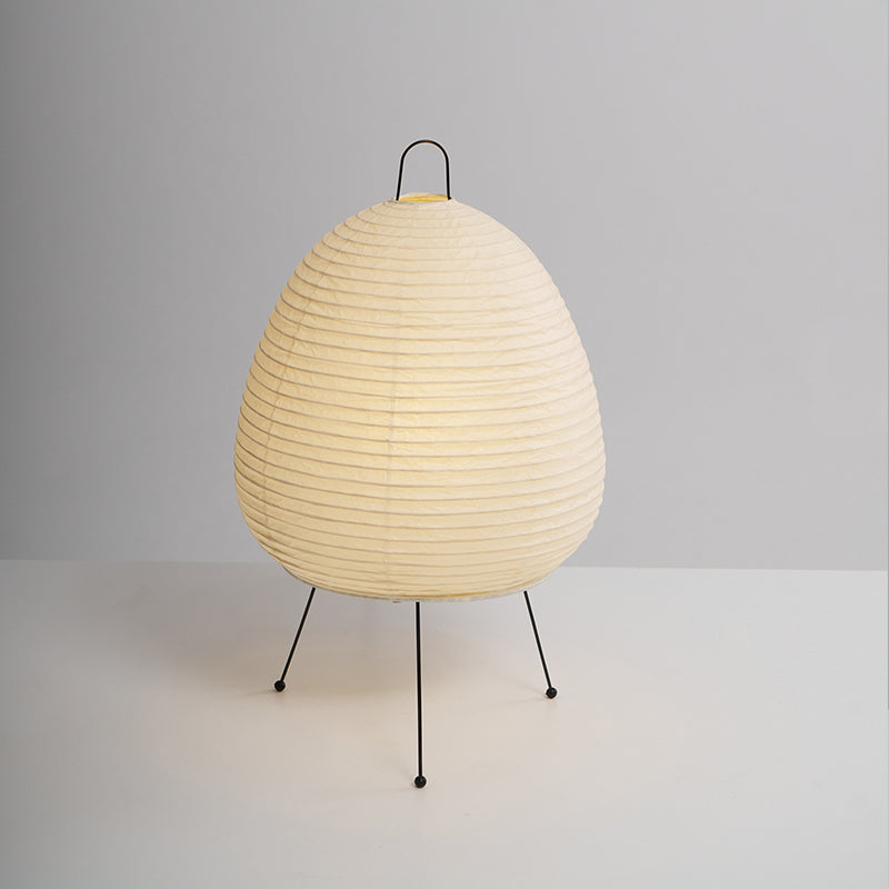 Egg-shaped Clérachic paper lamp on a plain grey backdrop, its shade finely ribbed above three black legs with round feet.