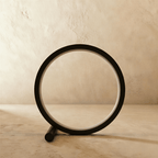 Clérachic black ring table lamp switched off, its pale acrylic diffuser visible inside the slim matt circle on a plaster backdrop.