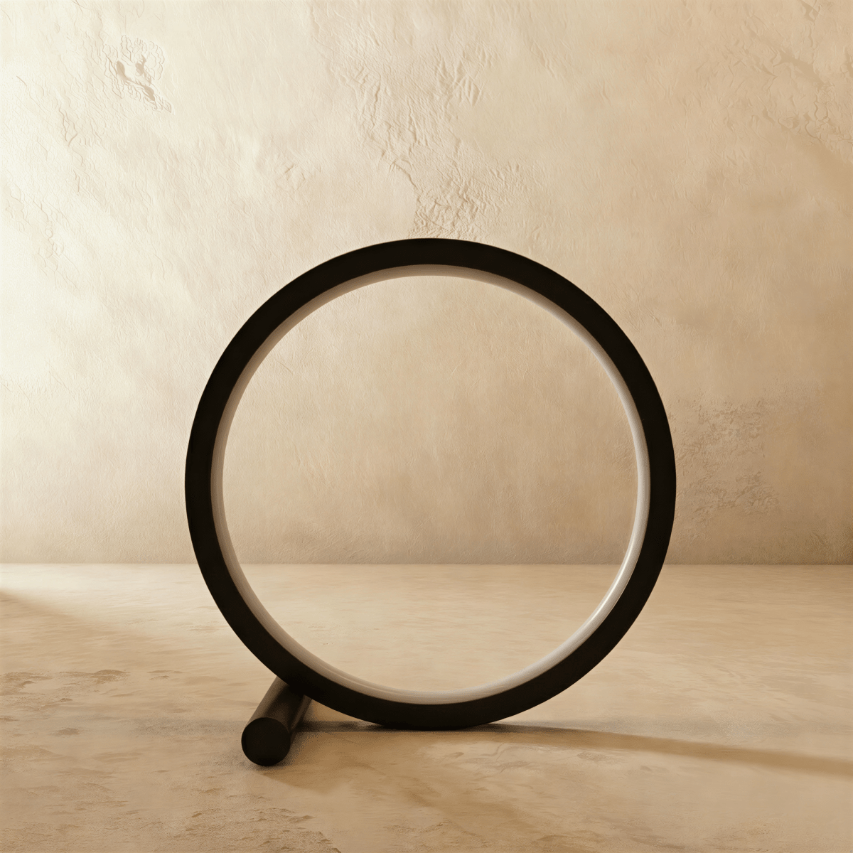 Clérachic black ring table lamp switched off, its pale acrylic diffuser visible inside the slim matt circle on a plaster backdrop.