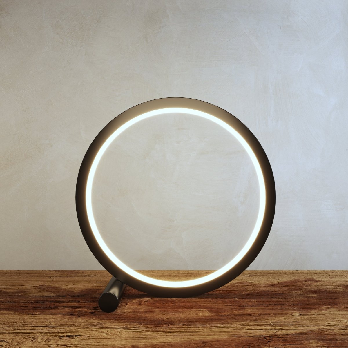 Clérachic black ring lamp lit warm on a rustic wooden tabletop, the glowing acrylic band running around the inside of the circle.