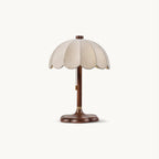 Clérachic table lamp with a scalloped beige fabric shade and a walnut-coloured stem on a clover-shaped base, on a plain white backdrop.