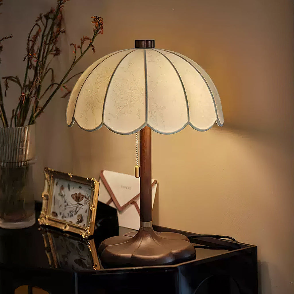 Close view of the shade edge and brass band on this Clérachic table lamp, with a photo frame on a dark glossy table.