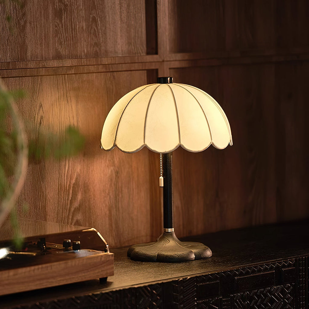 Clérachic table lamp with a black stem and a dark base, lit warm against wood panelling above a record player.