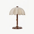 Clérachic table lamp in walnut colour and beige, with scalloped shade and pull chain, on a pale grey backdrop.
