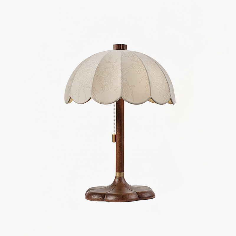 Clérachic table lamp in walnut colour and beige, with scalloped shade and pull chain, on a pale grey backdrop.