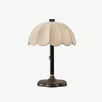 Clérachic table lamp in black and beige, with a dark stem and base under the scalloped shade, on a pale grey backdrop.