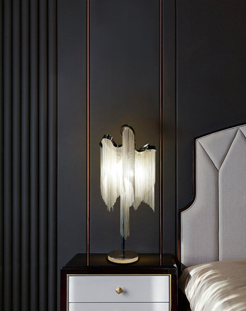 This Clérachic lamp glowing on a white bedside chest with a gold handle, set against a dark panelled wall and a grey headboard.