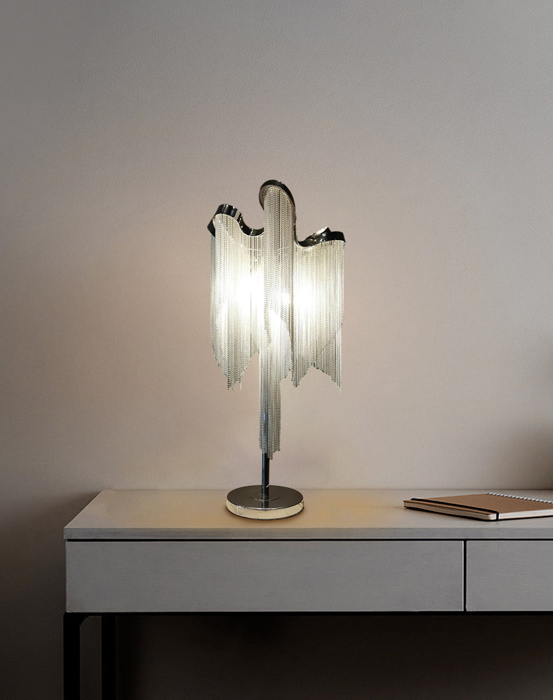 This Clérachic lamp lit on a grey console against a mauve wall, with a notebook lying on the desktop beside it.