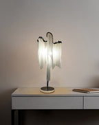 This Clérachic lamp lit on a grey console against a mauve wall, with a notebook lying on the desktop beside it.