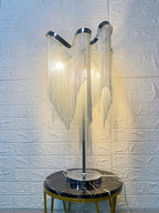 A lit Clérachic lamp on a black-marble stool with gold legs, in front of a white brick-pattern wall.