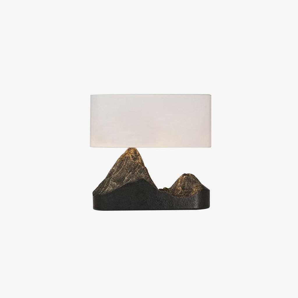 A small, straight-on Clérachic table lamp, a pale rectangular shade above a black base with two bronze-toned peaks, on white.