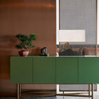 A Clérachic mountain-base table lamp on a green sideboard with brass legs, beside a bonsai and a small sculpture.