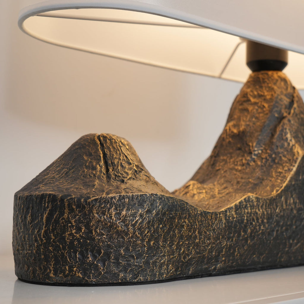 Close view of the rough, bronze-flecked ridges of this Clérachic table lamp's base, with the underside of the shade above.