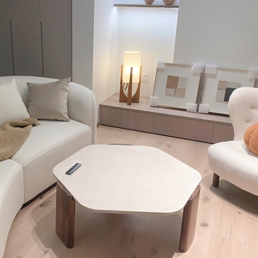 Clérachic wooden table lamp lit on a low shelf beside a cream sofa and a hexagonal coffee table in a living room.
