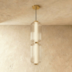 Clérachic two-tier ribbed glass pendant with gold fittings on a black cable, shown in the studio against a limewash wall.