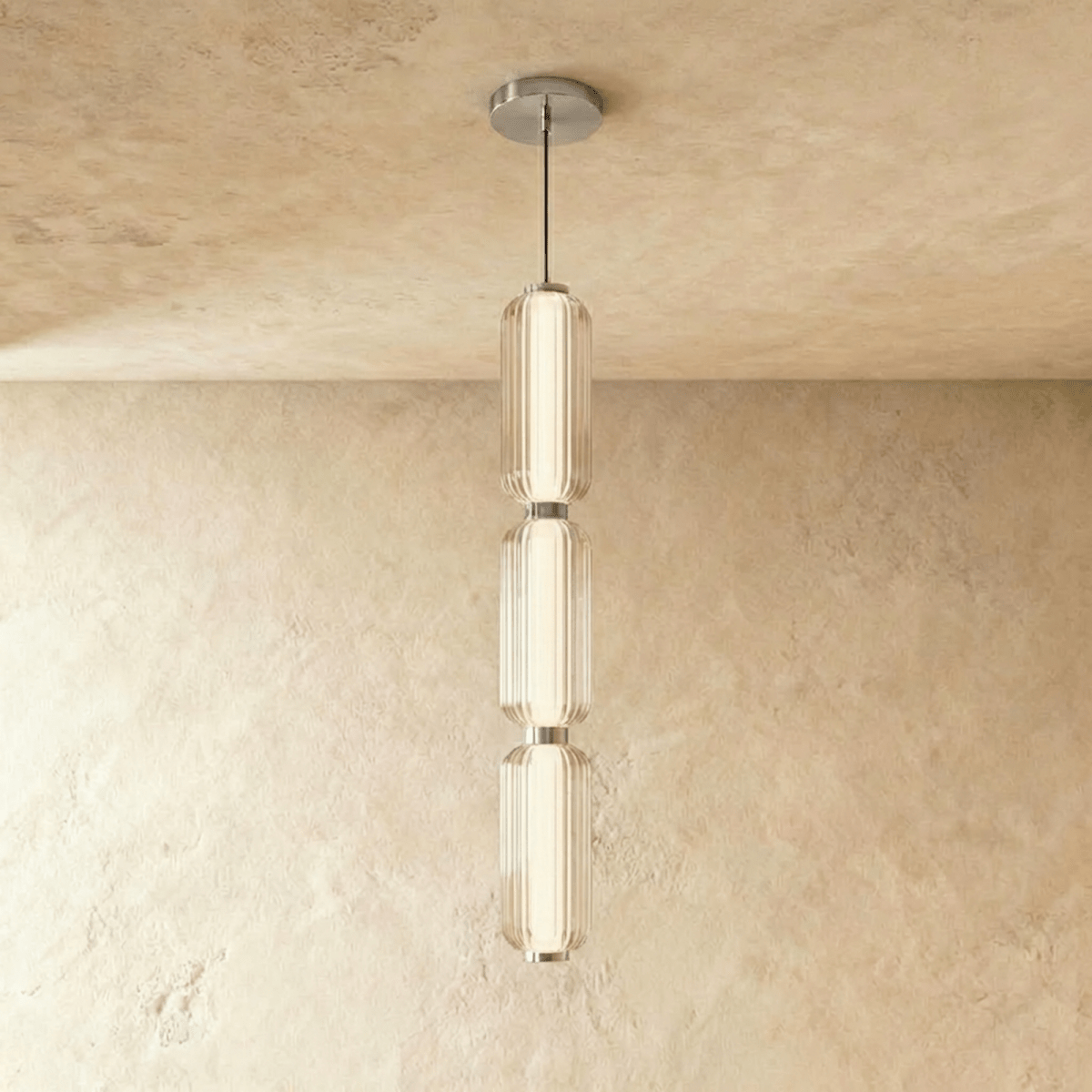 Clérachic three-tier ribbed glass pendant with chrome fittings, a tall glowing column hung in the studio on limewash.