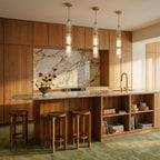 Clérachic three tall gold-capped ribbed glass pendants hung above a marble-topped timber kitchen island in a warm room.