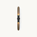 A tall slim wall light on a plain white backdrop: two matt black and gold tubes with open, angled mouths, from Clérachic.